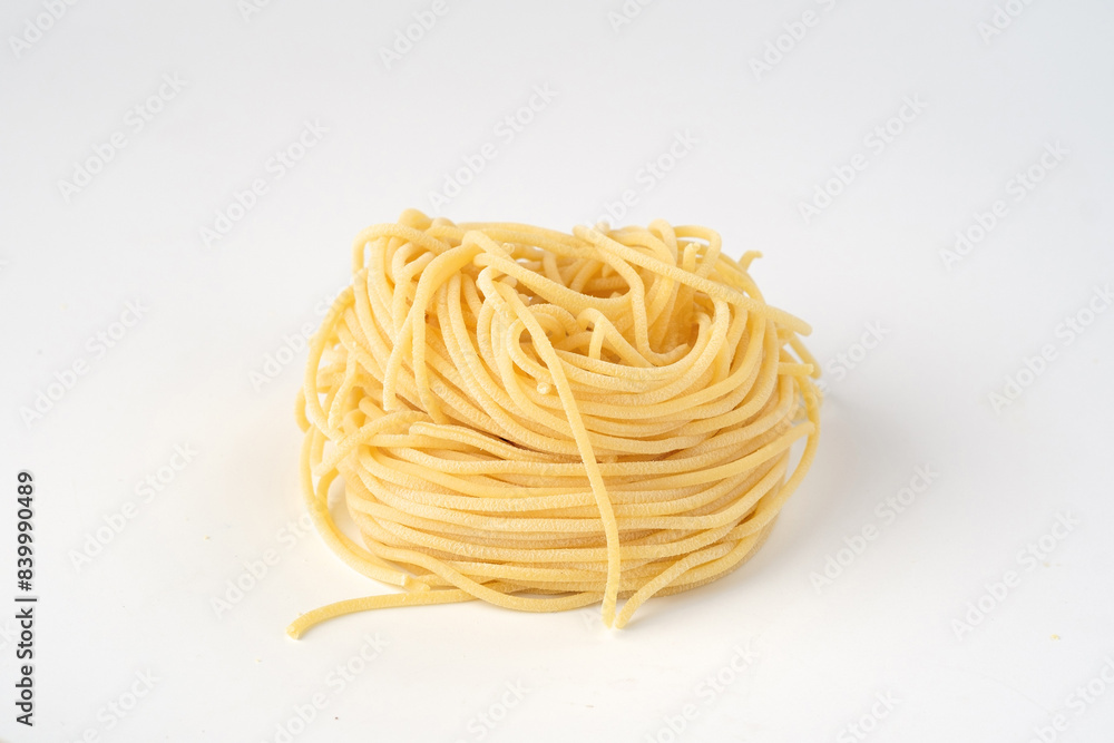 Egg Pasta spaghetti not cooked on a white background rolled into Egg Pasta spaghetti not cooked on a white background rolled into