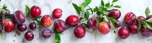 Australian plums arranged artistically on a white marble surface, with a hint of greenery and natural light photo