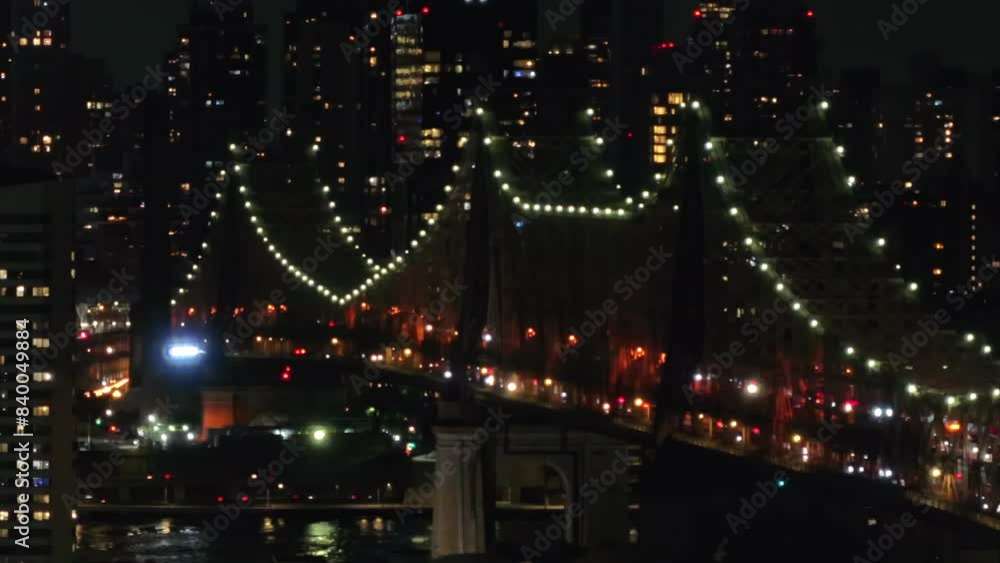 A high angle view of the 59th St., Bridge also known as the Ed Koch Queensboro Bridge. Taken at night, it is illuminated with cars driving across the span. The camera is stationary. A high angle view of the 59th St., Bridge also known as the Ed Koch Queensboro Bridge. Taken at night, it is illuminated with cars driving across the span. The camera is stationary.
