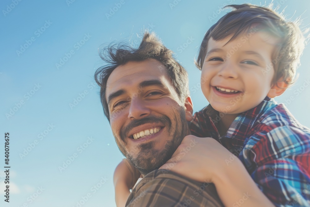 Playful father giving his son a piggyback ride against the sky. Portrait of a playful father giving his son a piggyback ride against the sky. Playful father giving his son a piggyback ride against the sky. Portrait of a playful father giving his son a piggyback ride against the sky.