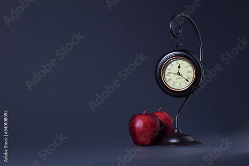 Red Apples and Clock with dark background.