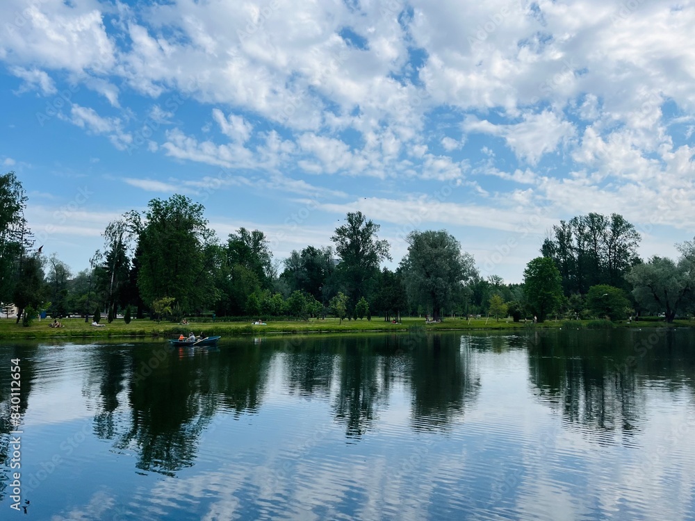 Obraz premium Green trees and sky reflection on the water surface, pond in the park
