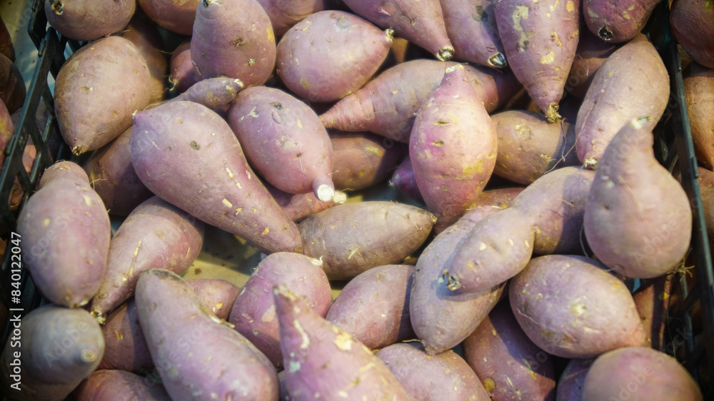 Stacks of purple sweet potatoes on display at a vegetable store Stacks of purple sweet potatoes on display at a vegetable store