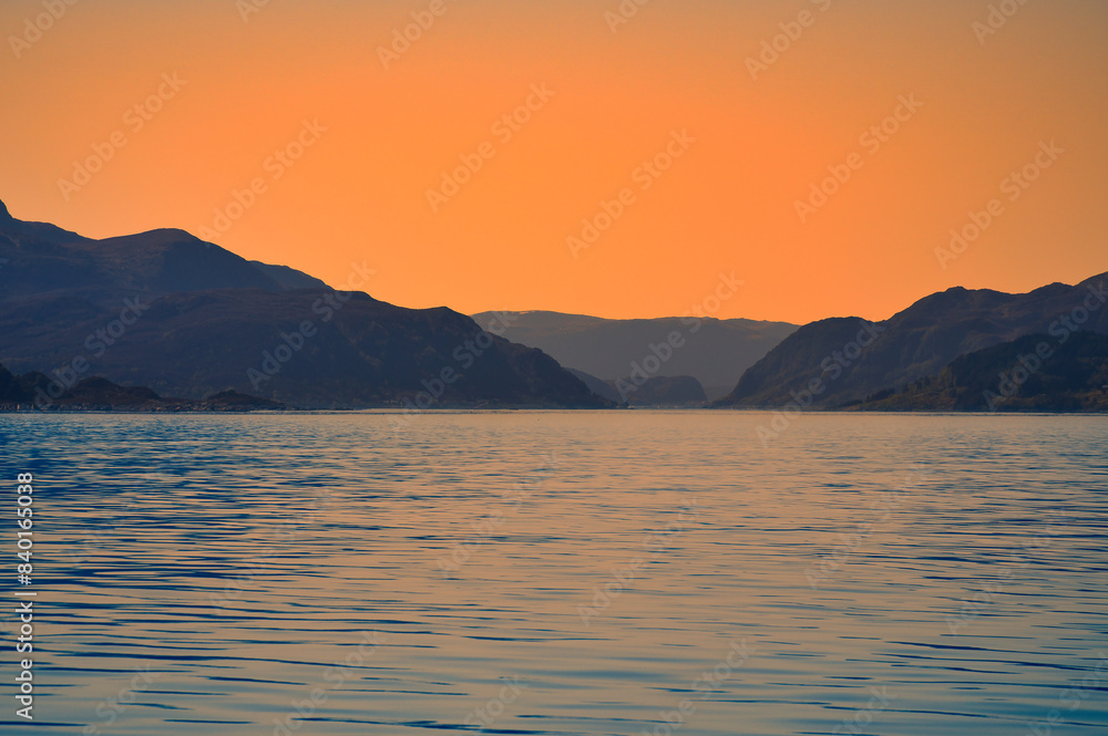 Norwegian fjord landscape at dusk. View of snow-capped mountains with rugged vegetation Norwegian fjord landscape at dusk. View of snow-capped mountains with rugged vegetation