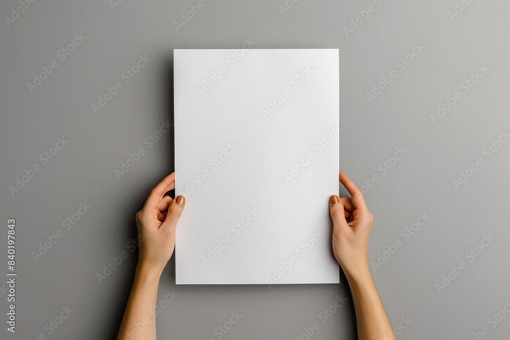 hands holding a blank paper sheet on a gray background in a top view mockup for artwork or design with copy space hands holding a blank paper sheet on a gray background in a top view mockup for artwork or design with copy space