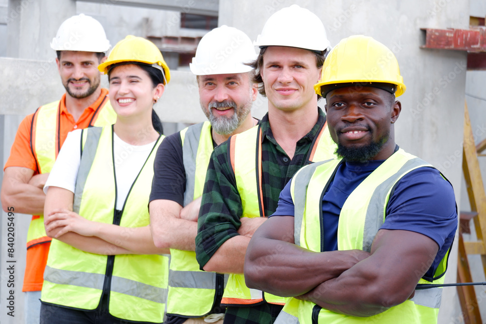 A team of male and female engineers stand smiling at a construction site for the housing industry. A team of male and female engineers stand smiling at a construction site for the housing industry.