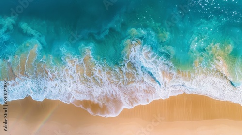 Vibrant shoreline seen from above, waves gently kiss the sand