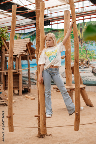 Casual girl posing on rustic swing in nature.