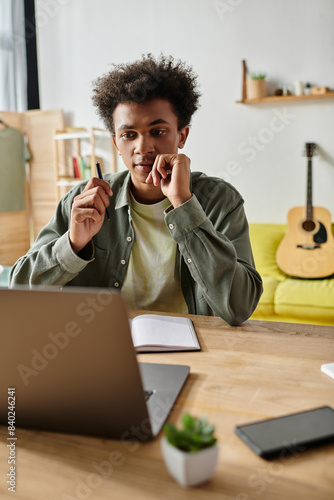 Картината върху платно Young man, laptop on desk, studying online at home.