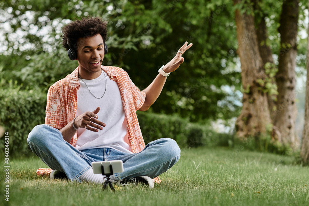 Young man of African descent sitting on grass, energetically pointing at phone. Young man of African descent sitting on grass, energetically pointing at phone.