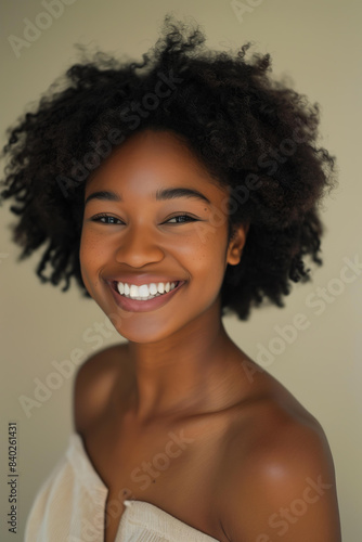African American woman smiling  glowing skin  with natural afro hairstyle  wearing minimal makeup  neutral beige background