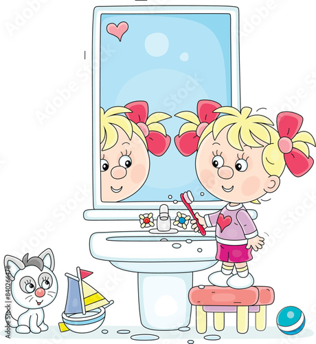 Funny little girl brushing her teeth at a mirror and washbasin in a bathroom with toys, vector cartoon illustration isolated on a white background