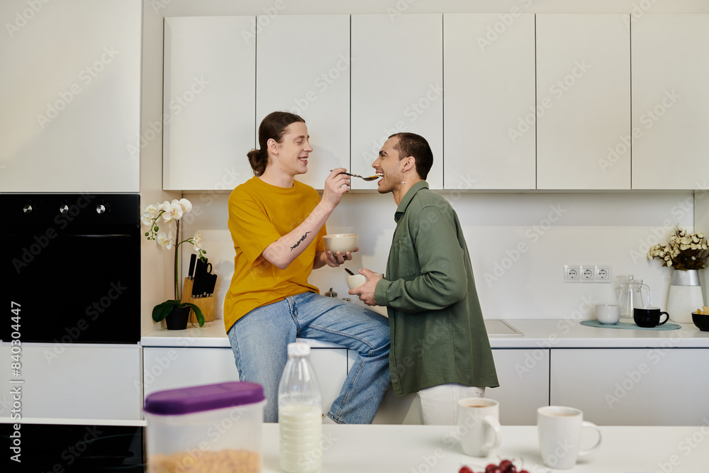 A young gay couple enjoys a playful moment in their modern kitchen, sharing breakfast and laughter. A young gay couple enjoys a playful moment in their modern kitchen, sharing breakfast and laughter.