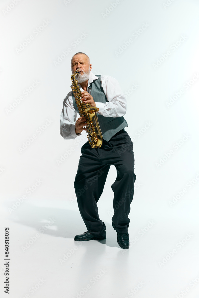 Naklejka premium Engagement with music. Bearded musician informal attire playing saxophone energetically against white studio background. Concept of music, festivals, contemporary art, hobby, creativity. Ad