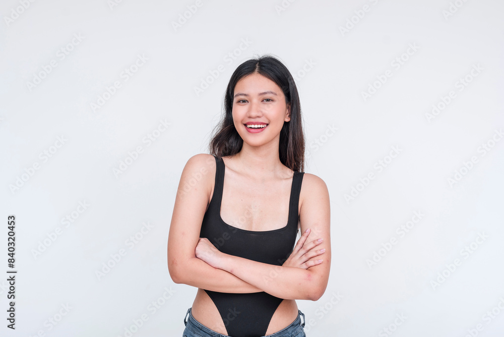 A cheerful young Asian woman wearing a black bodysuit, arms crossed looking at camera gleefully. Isolated on white background. A cheerful young Asian woman wearing a black bodysuit, arms crossed looking at camera gleefully. Isolated on white background.