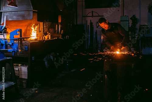 Blacksmith shaping metal on anvil in workshop