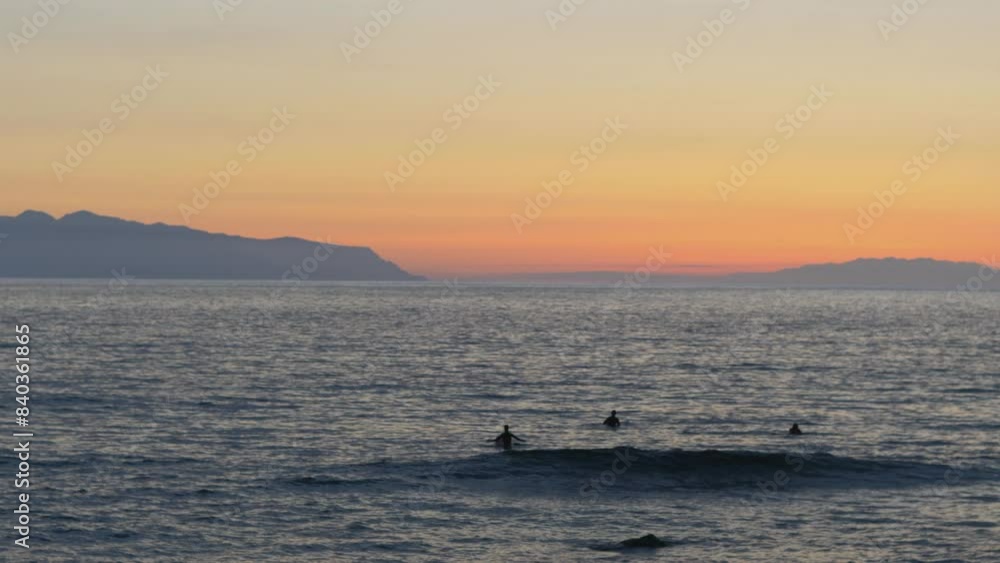 Surfers Catching Waves at Sunset Over the Ocean - A Spectacular Beach Scene in 4k slow motion 60fps Surfers Catching Waves at Sunset Over the Ocean - A Spectacular Beach Scene in 4k slow motion 60fps