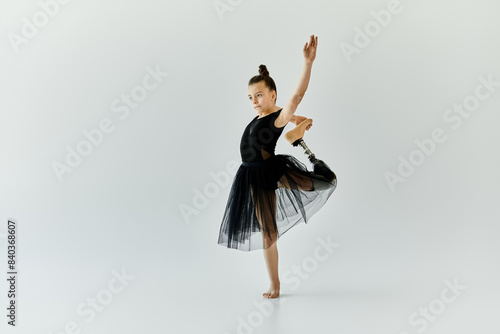 A young girl with a prosthetic leg performs a graceful ballet pose.