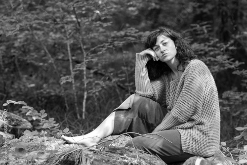 Portrait einer jungen Frau die entspannt im Wald sitzend Erholung findet photo