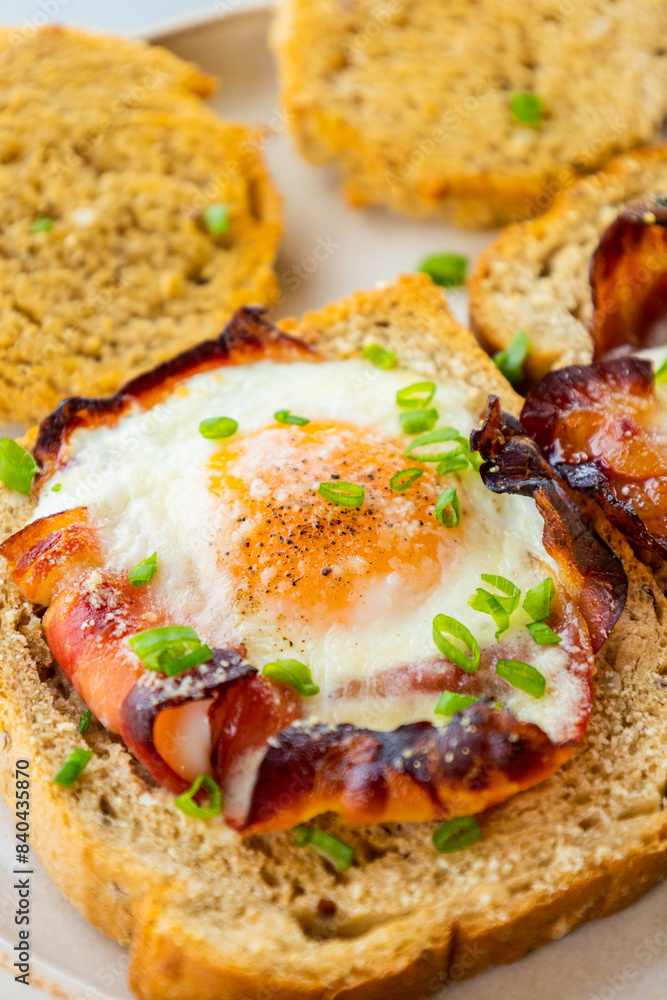 Baked Bacon and Eggs in Bread on White Plate with Fresh Green Onion Close-Up Baked Bacon and Eggs in Bread on White Plate with Fresh Green Onion Close-Up