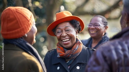 A diverse group of middle-aged people are smiling and laughing outdoors, dressed in winter attire with scarves and hats, against a snowy backdrop.