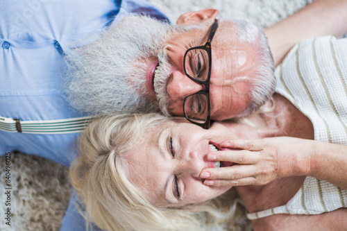 Senior couple lifestyle moments at home. Happy old woman and man laughing and havin fun on the carpet. photo