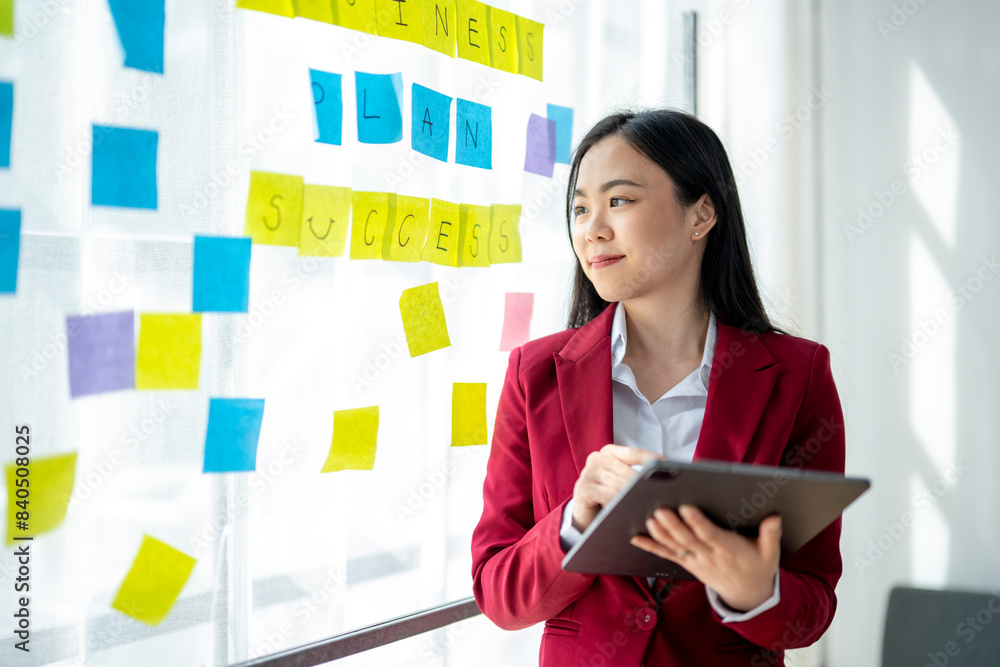A woman in a red jacket is looking at a white board with yellow A woman in a red jacket is looking at a white board with yellow