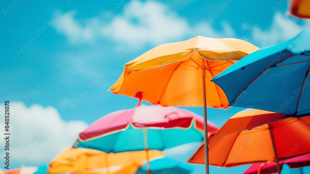 Colorful beach umbrellas against a bright blue sky on a sunny day, capturing the essence of a cheerful summer atmosphere at the coast.