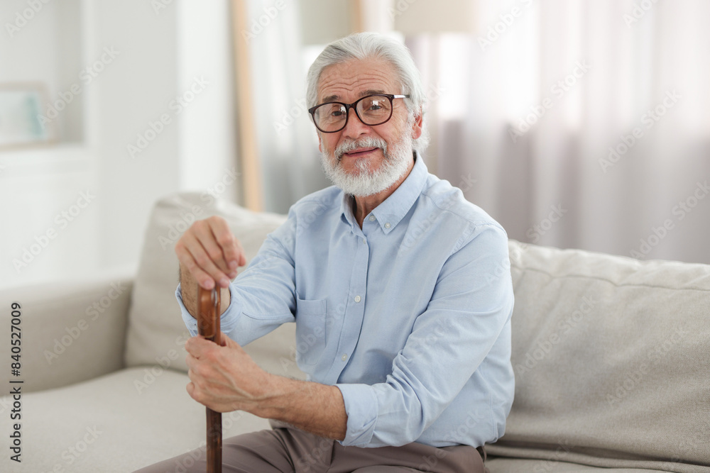 Portrait of grandpa with glasses and walking cane on sofa indoors Portrait of grandpa with glasses and walking cane on sofa indoors