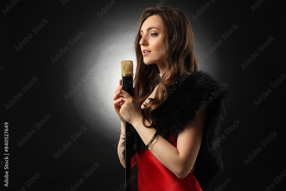 Beautiful young woman with microphone singing on black background Beautiful young woman with microphone singing on black background