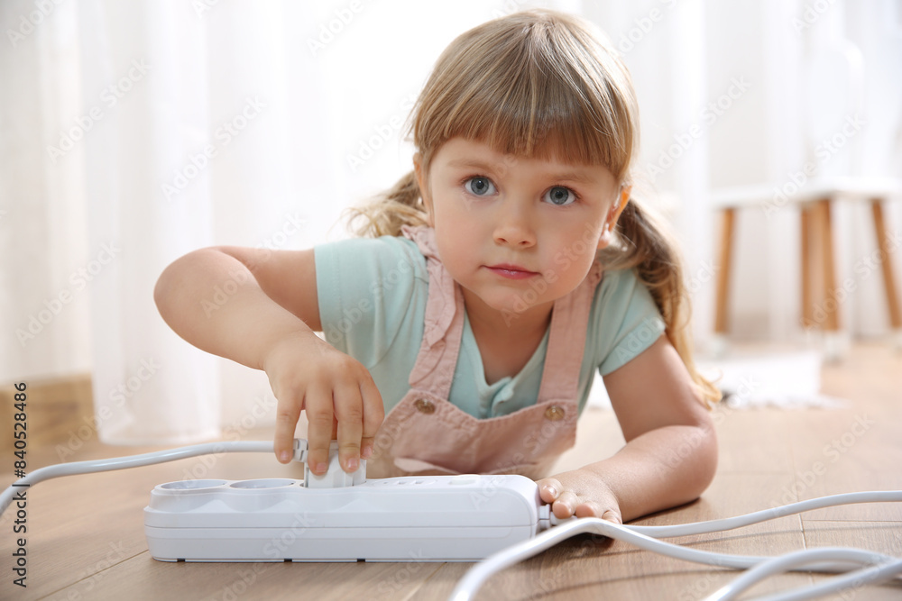 Little child playing with power strip and plug on floor indoors. Dangerous situation Little child playing with power strip and plug on floor indoors. Dangerous situation