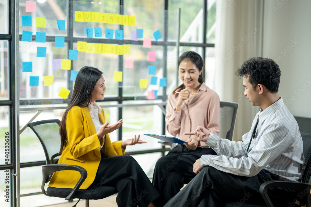 Three people are sitting in a room with a whiteboard behind them Three people are sitting in a room with a whiteboard behind them