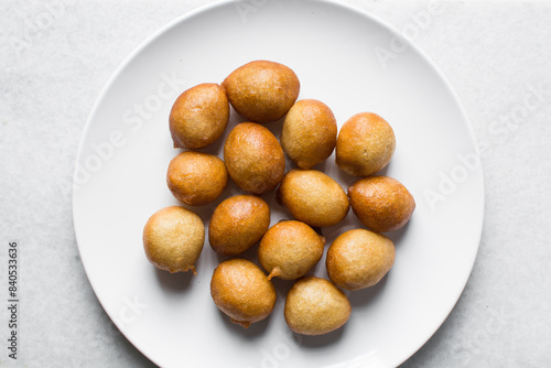 Overhead view of nigerian puff-puff on a white plate, nigerian fried dough balls, flatlay of homemade bofrot on white dish