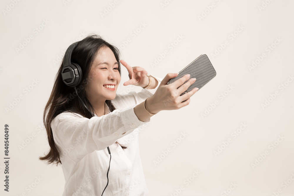 Portrait excited cute young woman taking a selfie and headphone isolated on white background.Beautiful woman smile taking selfie photo on cellphone.Beauty concept of middle aged Asian woman. Portrait excited cute young woman taking a selfie and headphone isolated on white background.Beautiful woman smile taking selfie photo on cellphone.Beauty concept of middle aged Asian woman.