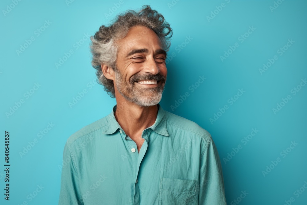 Portrait of a tender man in his 50s sporting a technical climbing shirt while standing against pastel teal background Portrait of a tender man in his 50s sporting a technical climbing shirt while standing against pastel teal background