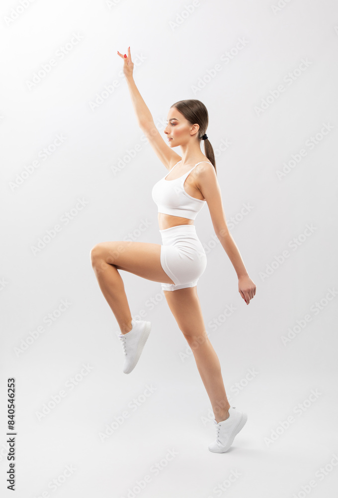 Slender dark-skinned female blogger in a white tracksuit against a white background. Healthy lifestyle, sports and diet. Slender dark-skinned female blogger in a white tracksuit against a white background. Healthy lifestyle, sports and diet.