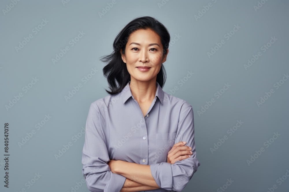 Portrait of a content asian woman in her 40s donning a classy polo shirt on pastel gray background Portrait of a content asian woman in her 40s donning a classy polo shirt on pastel gray background
