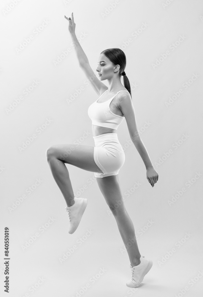 Beautiful attractive girl in white shorts and a top on a black background. The concept of sports and healthy lifestyle. Beautiful attractive girl in white shorts and a top on a black background. The concept of sports and healthy lifestyle.