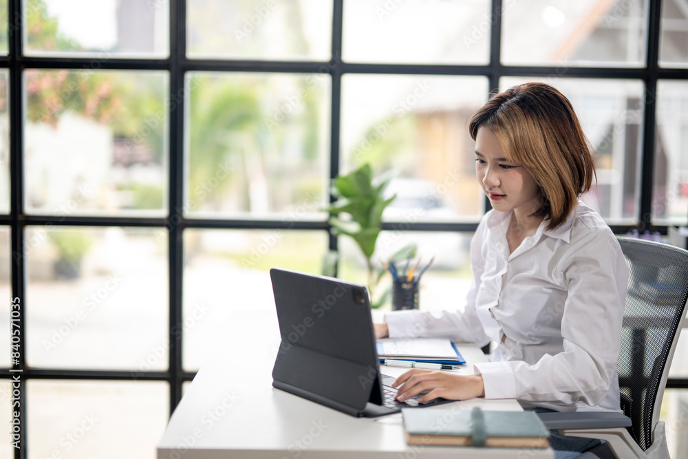 A woman is sitting at a desk with a laptop and a book A woman is sitting at a desk with a laptop and a book