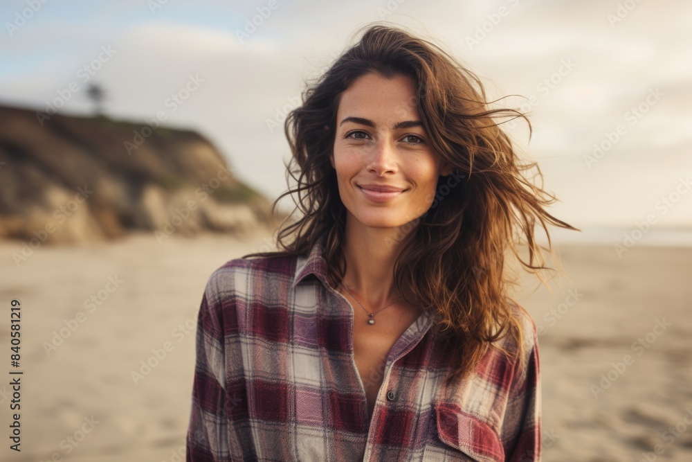 Portrait of a satisfied woman in her 20s dressed in a relaxed flannel shirt in sandy beach background Portrait of a satisfied woman in her 20s dressed in a relaxed flannel shirt in sandy beach background