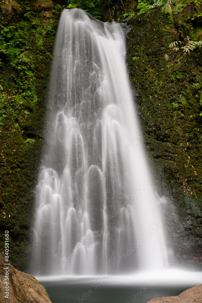 Obraz premium Waterfall Salto do Prego on the Isle of São Miguel, Azores, Portugal. Long exposure. Waterfall with tropical green vegetation and forests. Travel destination. Hiking on Azores Island.