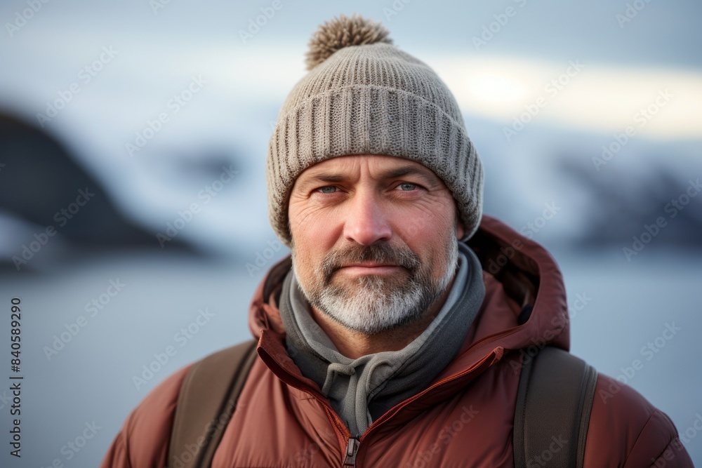 Portrait of a tender man in his 40s dressed in a warm ski hat while standing against serene seaside background Portrait of a tender man in his 40s dressed in a warm ski hat while standing against serene seaside background