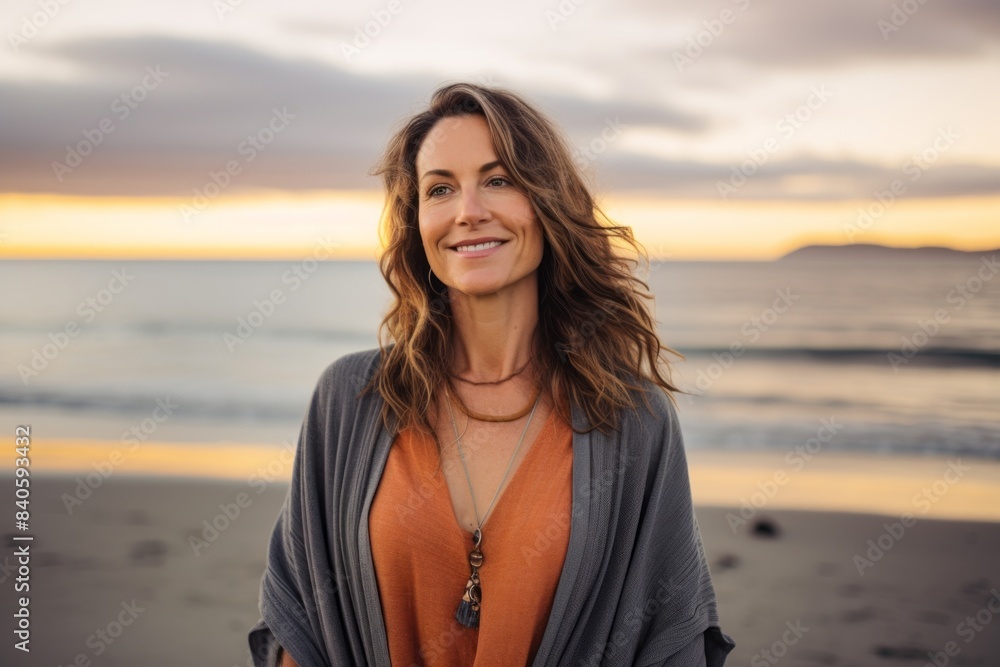 Portrait of a glad woman in her 40s wearing a chic cardigan isolated in stunning sunset beach background Portrait of a glad woman in her 40s wearing a chic cardigan isolated in stunning sunset beach background