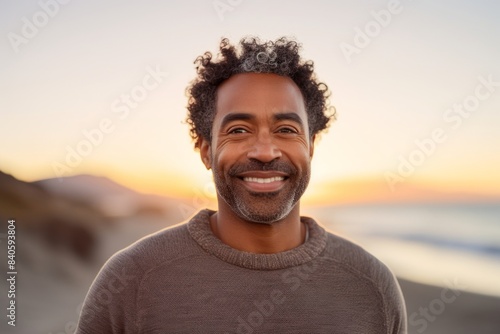 Portrait of a joyful afro-american man in his 40s dressed in a warm wool sweater on stunning sunset beach background