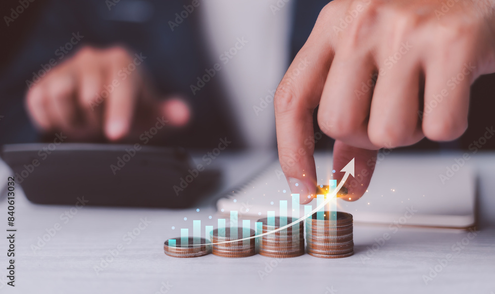 Investment and financial concept, businessman hand with money coin stacking and push arrow up to make a financial growth and profit, interest rates and dividends, investment returns, income, saving.