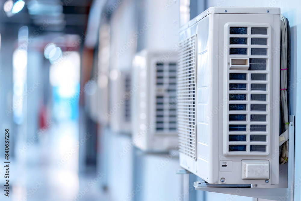 Close-up of air conditioning units in a bright, modern building hallway. Close-up of air conditioning units in a bright, modern building hallway.
