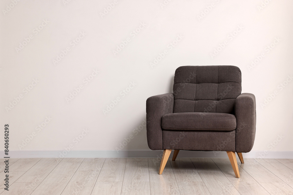 Comfortable armchair near white wall in room, space for text Comfortable armchair near white wall in room, space for text