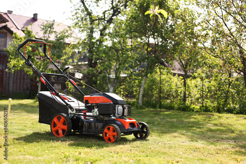 Modern lawn mower on green grass in garden