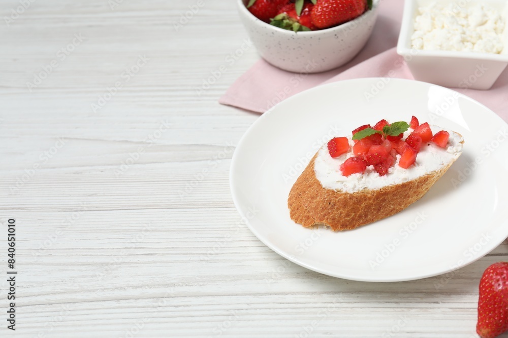 Delicious ricotta bruschetta with strawberry and mint on white wooden table. Space for text Delicious ricotta bruschetta with strawberry and mint on white wooden table. Space for text