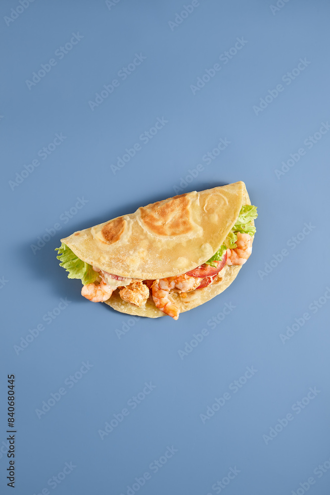 Fresh Shrimp Caesar Wrap on Pita Bread with Lettuce against Blue Background Fresh Shrimp Caesar Wrap on Pita Bread with Lettuce against Blue Background